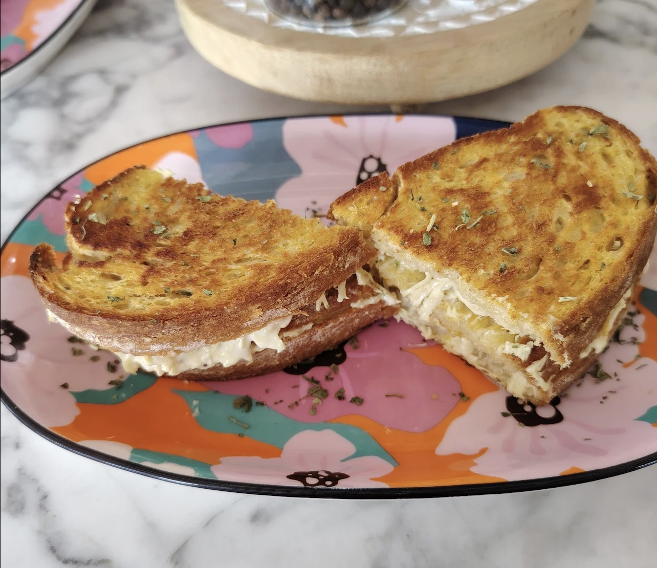Golden toasted sandwich cut in half on a floral plate