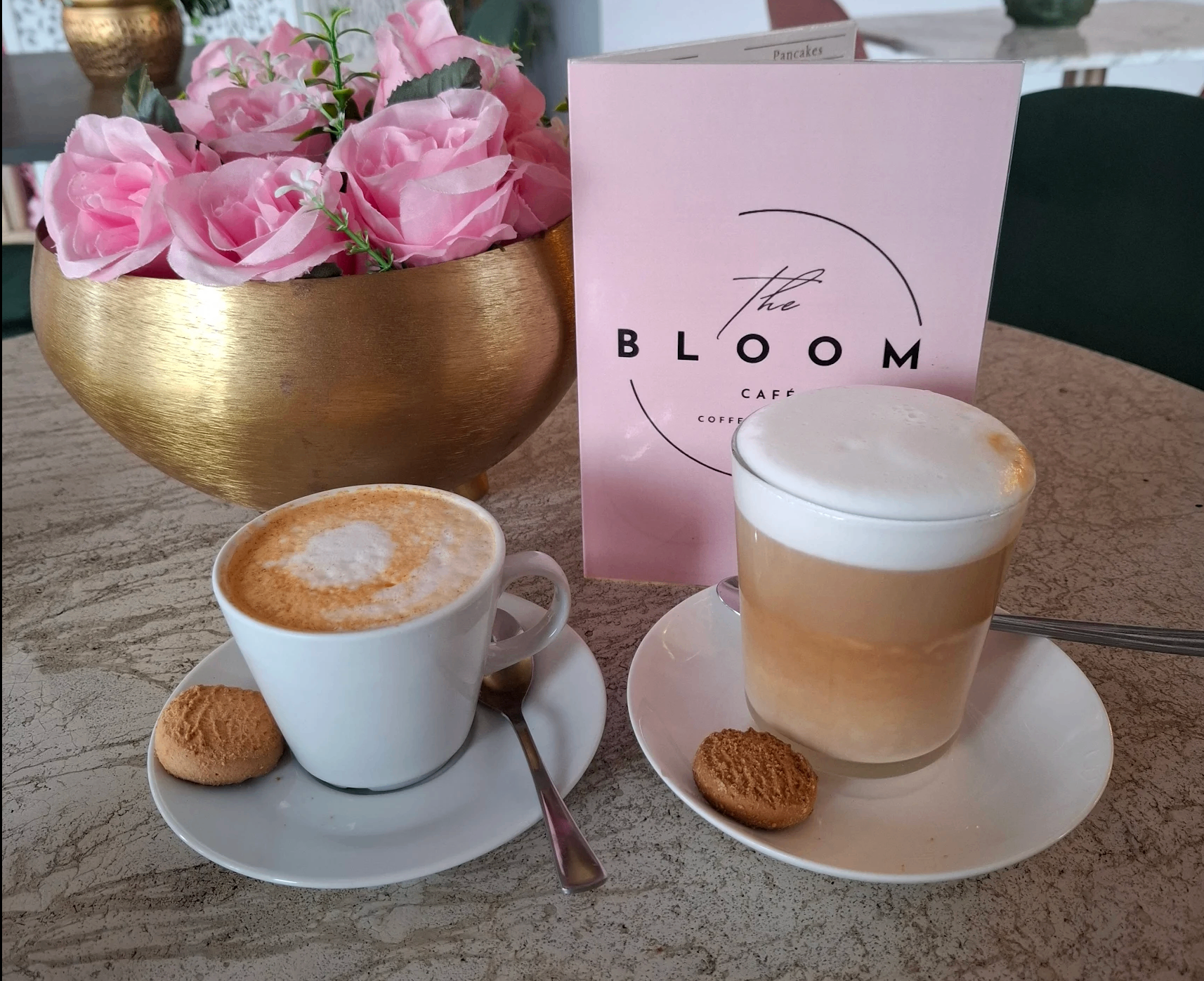 A cappuccino and glass latte with biscuits at The Bloom Café