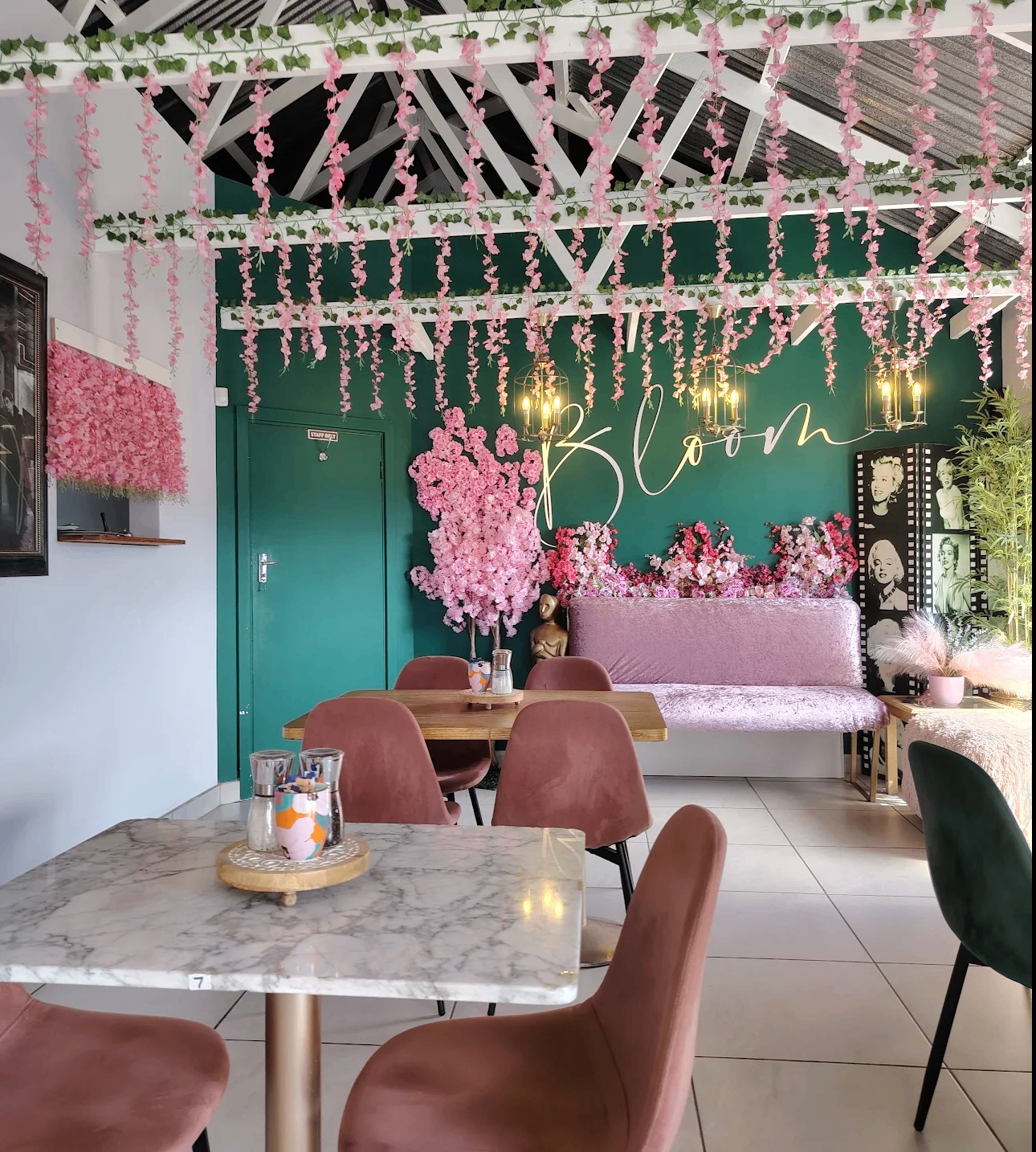 Interior tables at The Bloom Café with marble tops, velvet chairs and pink hanging blossoms